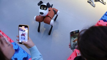 Pengunjung mencoba berinteraksi dengan anjing robot Baby Alpha. Foto: REUTERS/Florence Lo