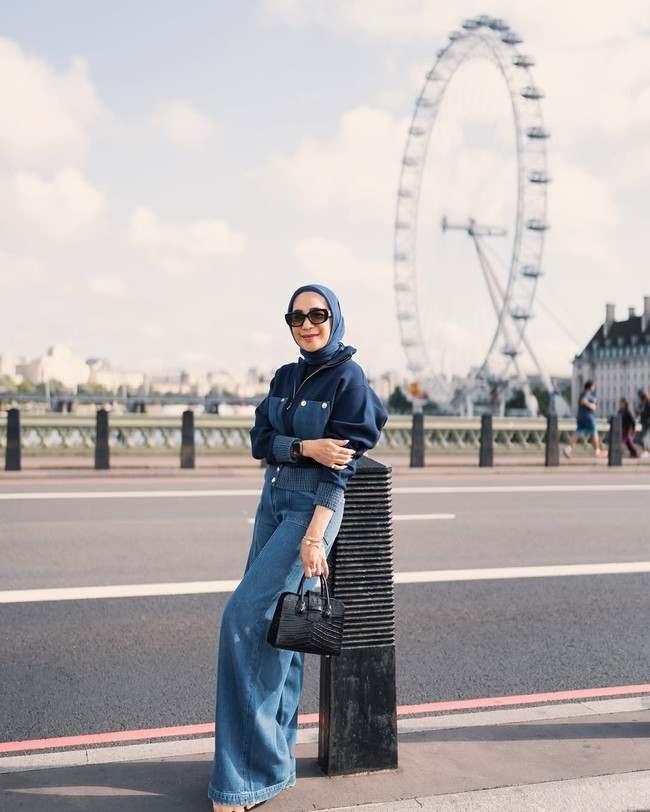 Bergaa denim on denim, Erin berpose dengan latar belakang landmark ikonik The London Eye di Inggris. Tas hitam dari kulit buaya melengkapi penampilannya. Foto: Instagram/@erintaulany