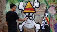 Kemas Muhammad Firdaus (28) tengah menggoreskan cat, membentuk ikon tengkorak Jolly Roger khas One Piece di dinding Bekasi, Kamis (7/8/2025). REUTERS/Ajeng Dinar Ulfiana