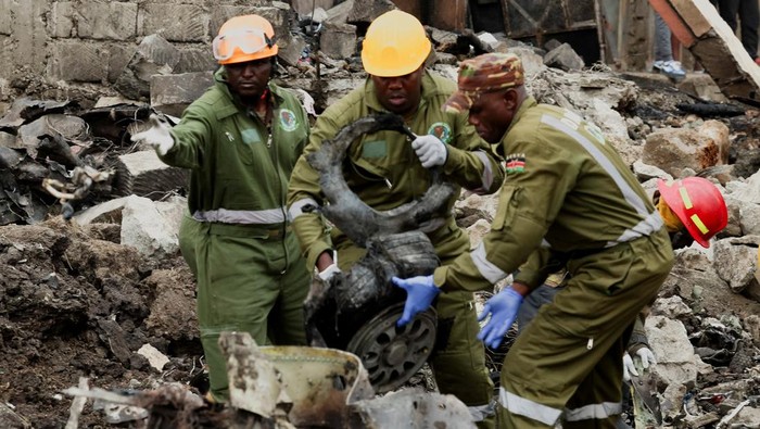 Rescuers gather near debris at the scene where a Cessna plane operated by AMREF Flying Doctors crashed into buildings in the Githurai suburb of northeastern Nairobi, Kenya, August 7, 2025. The aircraft, carrying four passengers, was en route to Hargeisa, the capital of Somalia's breakaway territory of Somaliland. REUTERS/Monicah Mwangi