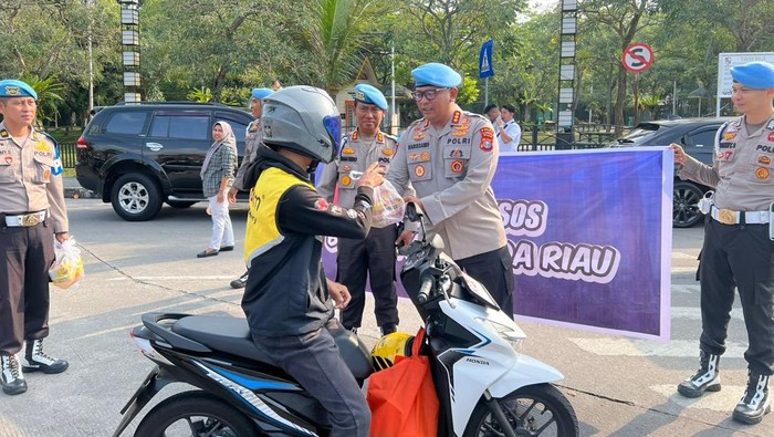 Propam Polda Riau turun ke jalan membagikan bansos kepada warga.