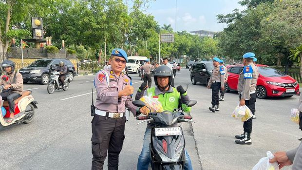 Propam Polda Riau turun ke jalan membagikan bansos kepada warga.