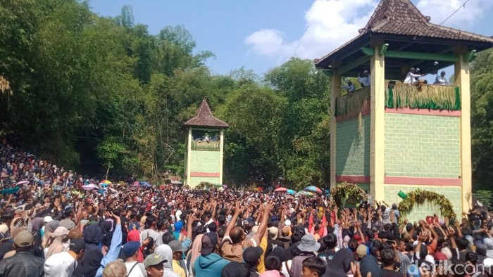 Ribuan warga berebut kue apem yang disebar dari atas menara di Klaten dalam puncak tradisi saparan, Jumat (8/8/2025).