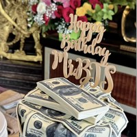 Kue ulang tahun Bambang terlihat unik dan mewah dengan dekorasi berbentuk lembaran-lembaran dollar AS. Pada bagian atasnya terdapat tulisan ‘Happy Birthday Mr. BTS’. Foto: Instagram/@mayangsari_official
