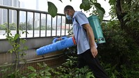 Petugas menyemprot disinfektan di jalan, permukiman, dan lokasi konstruksi. Beberapa titik bahkan disemprot sebelum warga memasuki gedung perkantoran. (Chen Chuhong/China News Service/VCG via Getty Images)