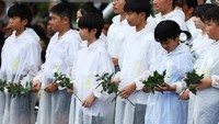 Sejumlah anak membawa bunga sebagai simbol doa dan harapan agar tragedi serupa tak pernah terulang di masa depan. REUTERS/Issei Kato