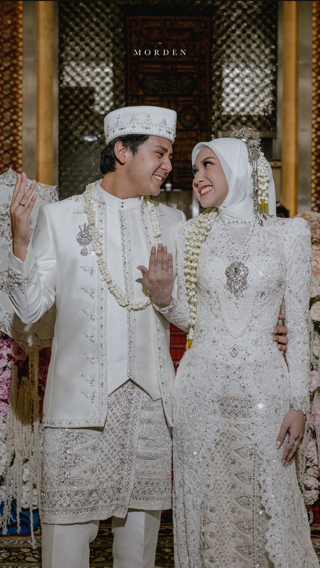 Keduanya tampil memukau dalam balutan busana pengantin berwarna putih dengan detail payet yang glamor, rancangan desainer Gugi Nugraha. Gaun Raissa berekor panjang, membuatnya terlihat anggun dalam balutan hijab. Foto: Instagram
