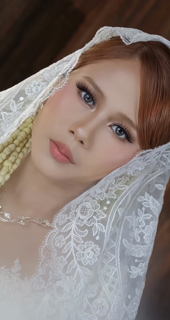 Ia melengkapi penampilannya dengan veil (kerudung panjang) berbahan tulle yang dipenuhi bordiran renda putih. Veil ini menyelimuti kepala hingga bagian bawah tubuh, memberi nuansa sakral sekaligus elegan. Foto: Instagram/@tyassofyamua