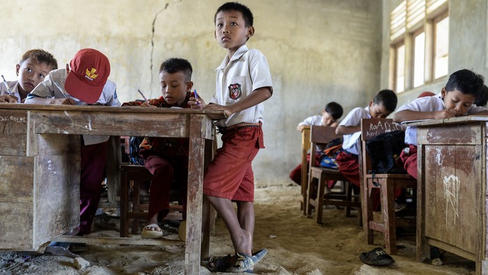 Sejumlah siswa kelas tiga menulis saat mengikuti kegiatan belajar mengajar di SD Negeri 1 Curug, Kecamatan Cibaliung, Pandeglang, Banten, Rabu (6/8/2025). Sebanyak dua ruang kelas sekolah tersebut kondisinya beralas tanah sejak tahun 2017 akibat proyek renovasi kelas yang mangkrak karena sulitnya membawa material bangunan menuju sekolah yang berada di pelosok Pandeglang itu. (ANTARA FOTO/Muhammad Bagus Khoirunas)