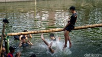 Mereka saling memukul dengan bantal untuk menjatuhkan lawan agar tercebur.