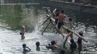 Para peserta beradu ketangkasan di atas sebilah kayu panjang sekitar empat meter yang dipasang melintang di atas sungai.