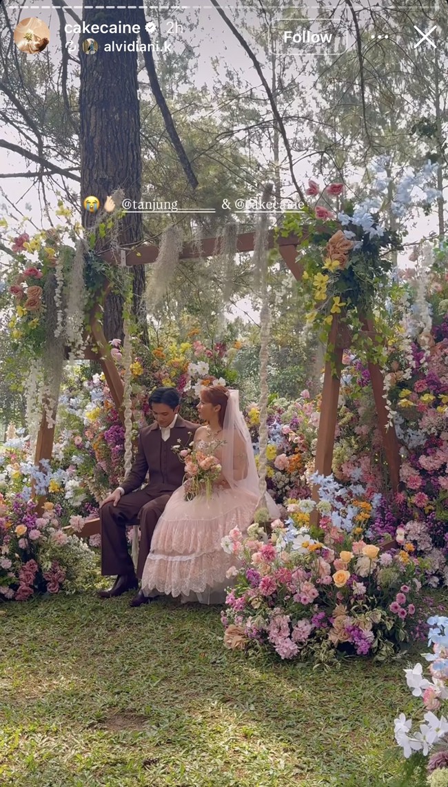 Bak di negeri dongeng, lokasi pernikahan yang berada di tengah hutan pinus itu dipercantik dengan dekorasi bunga-bunga yang berwarna-warni. Ada pula ayunan kayu dengan tali tambang putih tebal, dihiasi rangkaian bunga di bagian atasnya, menjadi salah satu spot foto di resepsi pernikahan Nadin dan Faishal. Foto: Instagram/@cakecaine