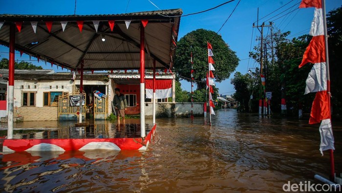 Warga beraktivitas di Perumahan Griya Satria Jingga, Bojong Gede, Kabupaten Bogor, Minggu (10/8/2025). Hujan deras sejak Sabtu (9/8) sore hingga malam membuat aliran kali di samping perumahan meluap.