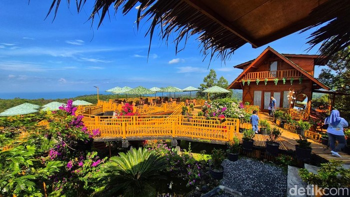 Pemandangan utama Bukit Durian Sagara Deretan meja berpayung hijau dan bangunan kayu bergaya villa berdiri di puncak bukit, menghadap langsung ke Teluk Palabuhanratu, dikelilingi bunga bougenville yang bermekaran.