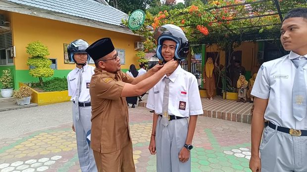 Ditlantas Polda Riau mengedukasi para siswa SMAN 12 Pekanbaru untuk menanam pohon sambil membagikan helm, Senin (11/8/2025).