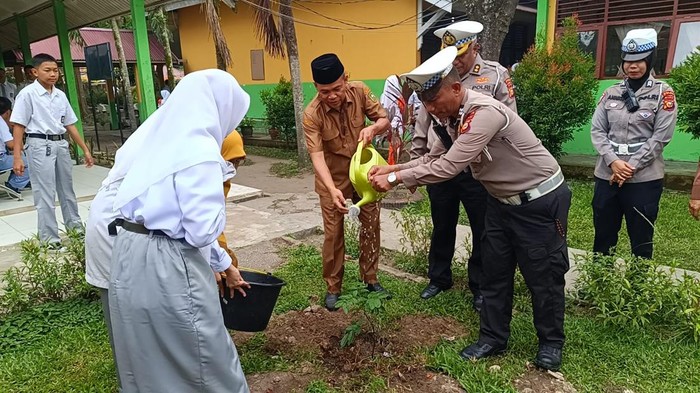 Ditlantas Polda Riau mengedukasi para siswa SMAN 12 Pekanbaru untuk menanam pohon sambil membagikan helm, Senin (11/8/2025).