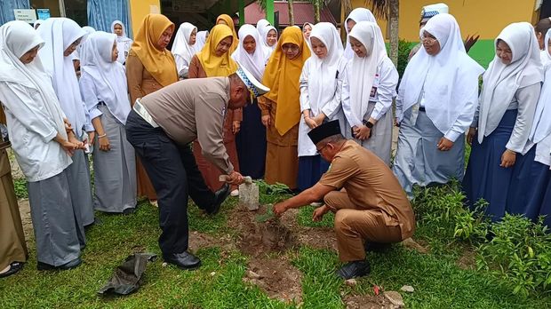 Ditlantas Polda Riau mengedukasi para siswa SMAN 12 Pekanbaru untuk menanam pohon sambil membagikan helm, Senin (11/8/2025).