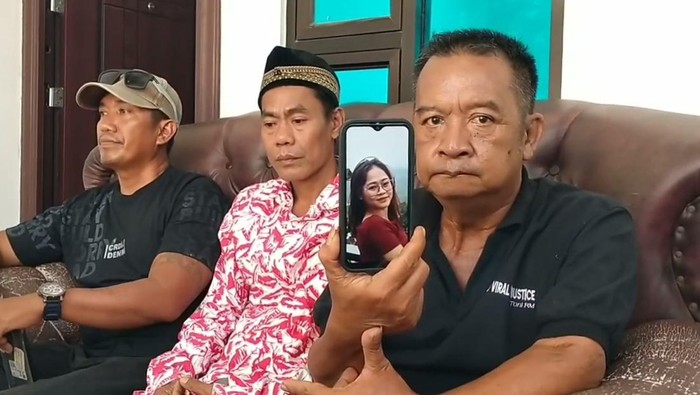 Keluarga korban menunjukkan foto Putri Apriani