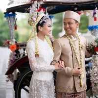 Aksen brokat di bagian dada dan kancing tersembunyi memberi kesan sleek, sementara lipatan kain batik Betawi di bagian pinggang menjadi pengikat visual yang menyelaraskan busana kedua mempelai. Foto: Instagram/@fcbweddings