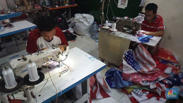 Pekerja melipat bendera di usaha konveksi rumahan yang memproduksi bendera umbul-umbul merah putih, topi, hingga kaos di kawasan Tangerang Selatan, Banten, Senin (11/8/2025). (CNBC Indonesia/Muhammad Sabki)