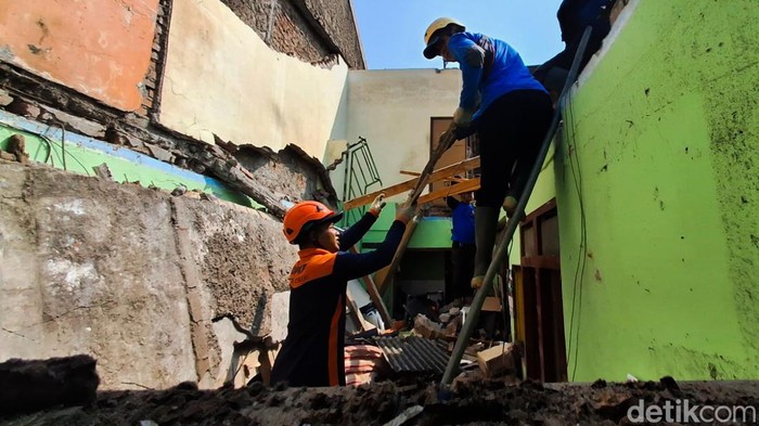 Petugas dan relawan BPBD Kota Cimahi bersihkan material di rumah ambruk.