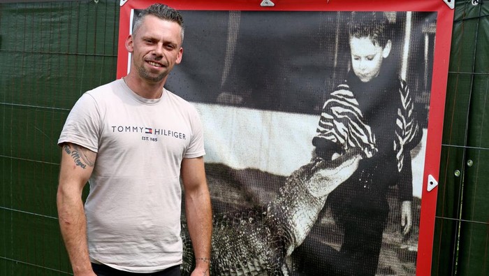 Former circus artist Krystian Kaulis pets Mrs Meyer, an American alligator, as he takes a swim in the outdoor pool in Elmenhorst, Germany, August 1, 2025. REUTERS/Lisi Niesner