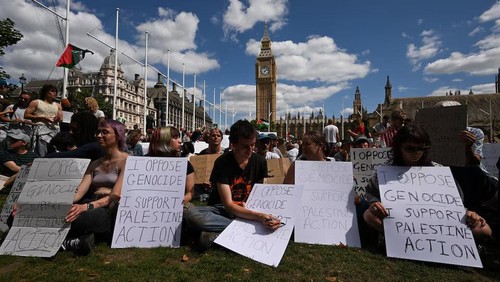 People holding signs sit during a rally organised by Defend Our Juries, challenging the British governments proscription of Palestine Action under anti-terrorism laws, in Parliament Square, in London, Britain, August 9, 2025. REUTERS/Jaimi Joy Purchase Licensing Rights