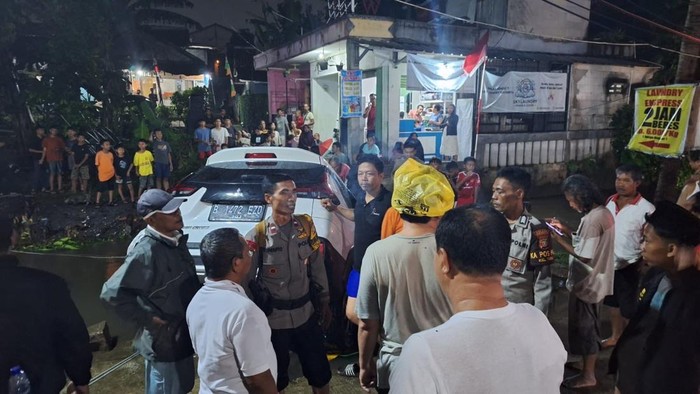 Warga membantu mengevakuasi mobil yang terseret banjir dan nyaris menyeret sekeluarga di Cimanggis, Depok.
