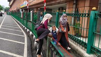 Warga terlihat nekat melompati pagar Stasiun KAI Cikini, Jakarta Pusat, Selasa (12/8/2025). Aksi ini masih menjadi pemandangan sehari-hari.  