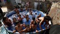 Kolam kecil menjadi tempat favorit anak-anak untuk bermain air, melupakan sejenak teriknya matahari musim panas. Foto: REUTERS/Mohamed Abd El Ghany