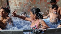 Tanpa harus pergi jauh, warga memanfaatkan kolam portabel untuk memberi anak-anak ruang aman dan sejuk bermain air. Foto: REUTERS/Mohamed Abd El Ghany