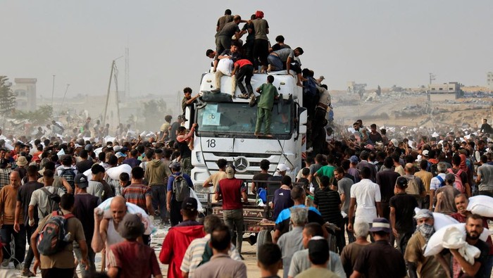 Palestinians scramble to collect aid supplies from trucks that entered through Israel, in Khan Younis, southern Gaza Strip, August 12, 2025. REUTERS/Hatem Khaled     TPX IMAGES OF THE DAY