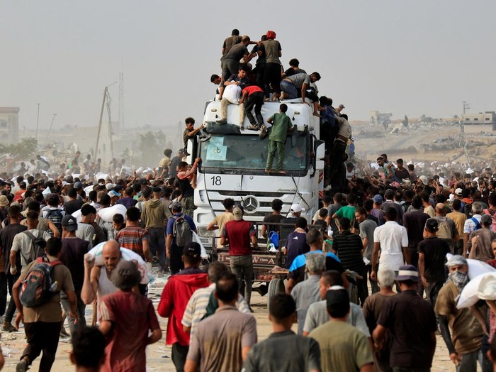 Palestinians scramble to collect aid supplies from trucks that entered through Israel, in Khan Younis, southern Gaza Strip, August 12, 2025. REUTERS/Hatem Khaled     TPX IMAGES OF THE DAY