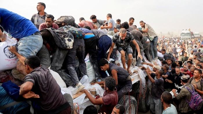 Palestinians scramble to collect aid supplies from trucks that entered through Israel, in Khan Younis, southern Gaza Strip, August 12, 2025. REUTERS/Hatem Khaled     TPX IMAGES OF THE DAY