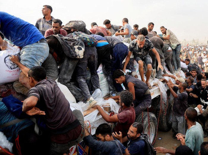 Palestinians scramble to collect aid supplies from trucks that entered through Israel, in Khan Younis, southern Gaza Strip, August 12, 2025. REUTERS/Hatem Khaled TPX IMAGES OF THE DAY