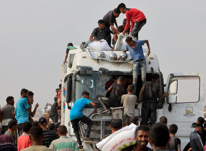 Palestinians scramble to collect aid supplies from trucks that entered through Israel, in Khan Younis, southern Gaza Strip, August 12, 2025. REUTERS/Hatem Khaled     TPX IMAGES OF THE DAY