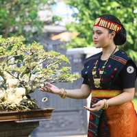 Rambut Amora disanggul rapi dengan sentuhan modern, dihiasi hiasan kepala merah dan emas yang menjadi ciri khas busana adat Batak, membuat penampilannya semakin megah. Foto: Instagram/@amora_lemos05