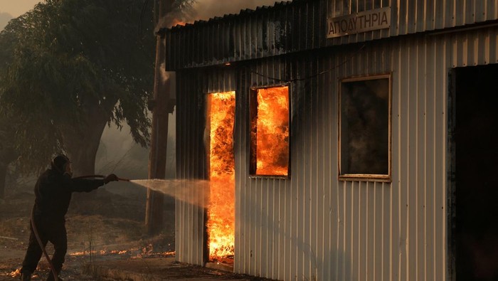 Api Kebakaran Hutan di Yunani Menjalar ke Permukiman Warga Firefighters work to extinguish a fire from a building during a wildfire, in Sichaina near Patras, Greece, August 13, 2025. REUTERS/Louiza Vradi