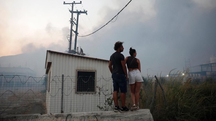 Firefighters work to extinguish a fire from a building during a wildfire, in Sichaina near Patras, Greece, August 13, 2025. REUTERS/Louiza Vradi
