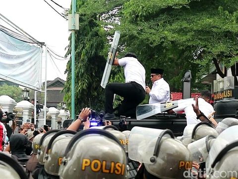 Bupati Pati Sudewo menemui massa aksi di depan kantornya, Rabu (13/8/2025). Tampak ajudannya berupaya pasang badan cegah Sudewo terkena lemparan botol.