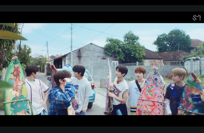 Keenam personel NCT WISH tampak membawa papan selancar dan siap bersenang-senang di pantai. Tak sedikit penggemar yang menyinggung Carmen, personel grup KPop Hearts2Hearts dari agensi yang sama dalam lelucon, yang mungkin iri dan berharap bisa ikut personel NCT WISH pulang kampung. Foto: dok. SM Entertainment