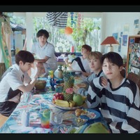 Tampak beberapa buah-buahan eksotis Indonesia sebagai properti seperti buah naga, pisang, kelapa, mangga, dan nanas dalam adegan personelnya berkumpul di meja makan, berbusana putih dan celana pendek. Foto: dok. SM Entertainment