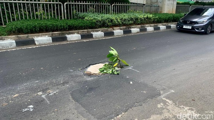 Ada lubang terlihat di tengah Jalan Kapten Tendean, Jakarta Selatan. Lubang tersebut hanya di beri pasir putih dan daun sebagai tanda.