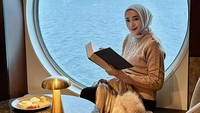 Gaya keren Erin juga terliht ketika berada di sebuah kafe yang menghadap ke laut di Norwegia. Ia tampak berpose ala membaca buku dengan hidangan cheese platter di hadapannya. Foto: Instagram/@erintaulany