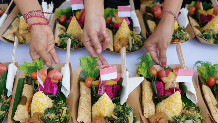 Peserta membagikan makanan yang diolah dari bahan pangan lokal kepada warga saat Festival Pangan dan Cipta Menu Bergizi di Desa Sumerta Kelod, Denpasar, Bali, Kamis (14/8/2025). Festival yang digelar dalam rangka memperingati Hari Ulang Tahun ke-80 Kemerdekaan Republik Indonesia dan Hari Jadi ke-67 Provinsi Bali tersebut diikuti puluhan warga dengan nuansa merah putih yang bertujuan memperkuat ketahanan pangan dengan memberdayakan potensi lokal serta mengembangkan keterampilan warga khususnya di bidang kuliner guna kedepannya membuka peluang untuk berwirausaha. ANTARA FOTO/Nyoman Hendra Wibowo/bar