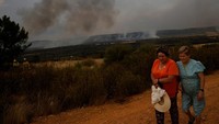 Dua perempuan berjalan menjauh setelah menyaksikan kebakaran hutan di Abejera de Tabara, Zamora, Spanyol, Rabu (13/8/2025). Kekeringan parah membuat vegetasi sangat kering dan mudah terbakar, memicu kebakaran di beberapa negara sekaligus. REUTERS/Susana Vera