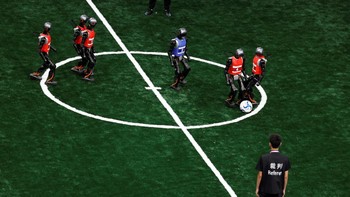 Robot humanoid Booster Robotics T1 bertanding dalam laga sepak bola lima lawan lima di World Humanoid Robot Games perdana di National Speed Skating Oval, Beijing, China, Jumat (15/8/2025). Pertandingan ini menampilkan kerjasama tim antarrobot di lapangan hijau. REUTERS/Tingshu Wang  