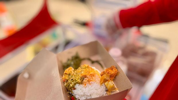 Dino mempersiapkan pesanan nasi Padang dari pembeli.