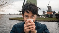 Liburan ke Belanda, ini momen pria kelahiran Sumatera Utara saat menikmati cokelat hangat topping marshmallow dengan pemandangan kincir angin. Foto: Instagram/@kennyauztin