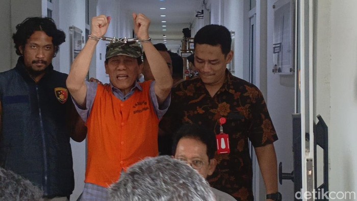 Bambang Raya mengangkat borgolnya sebelum dibawa ke Lapas Kelas 1 Semarang , Semarang (15/8/2025).